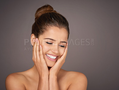 Buy stock photo Studio shot of a beautiful young woman feeling her skin against a gray background