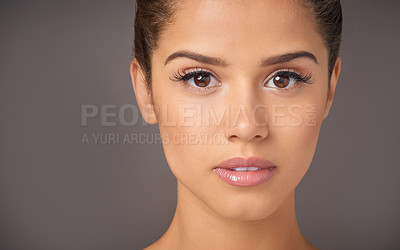 Buy stock photo Studio portrait of a beautiful young woman with flawless skin posing against a gray background