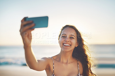 Buy stock photo Cropped shot of a young woman taking a selfie on the beach
