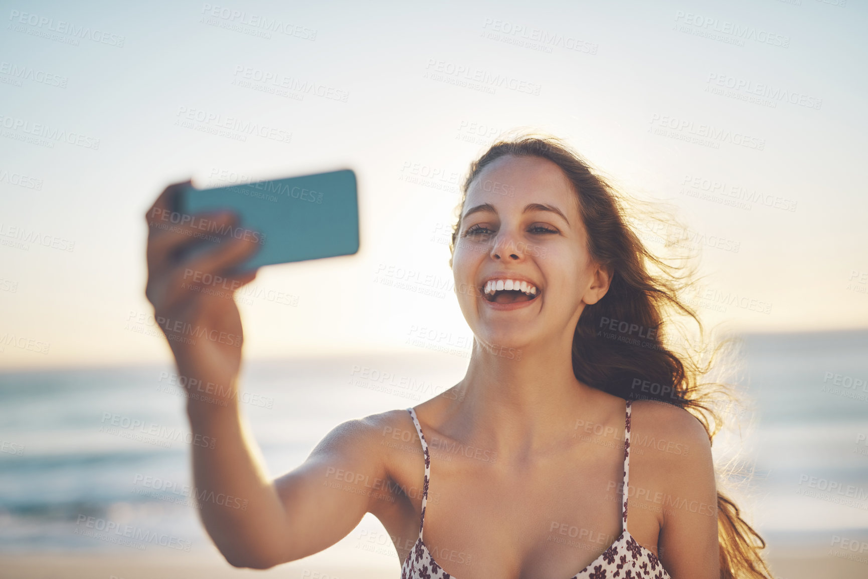 Buy stock photo Cropped shot of a young woman taking a selfie on the beach