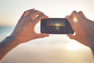 Buy stock photo Cropped shot of a person taking a picture of the sunset at the beach