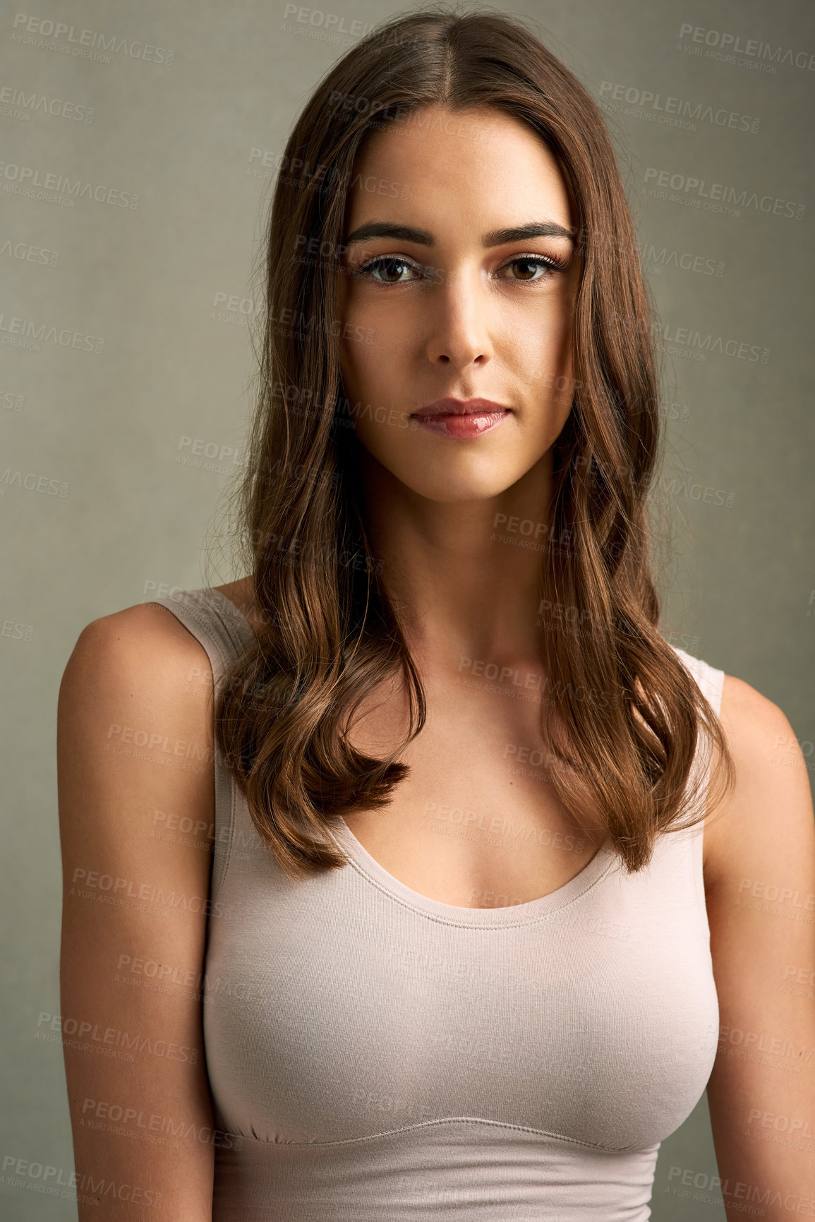 Buy stock photo Studio portrait of an attractive young woman standing against a brown background