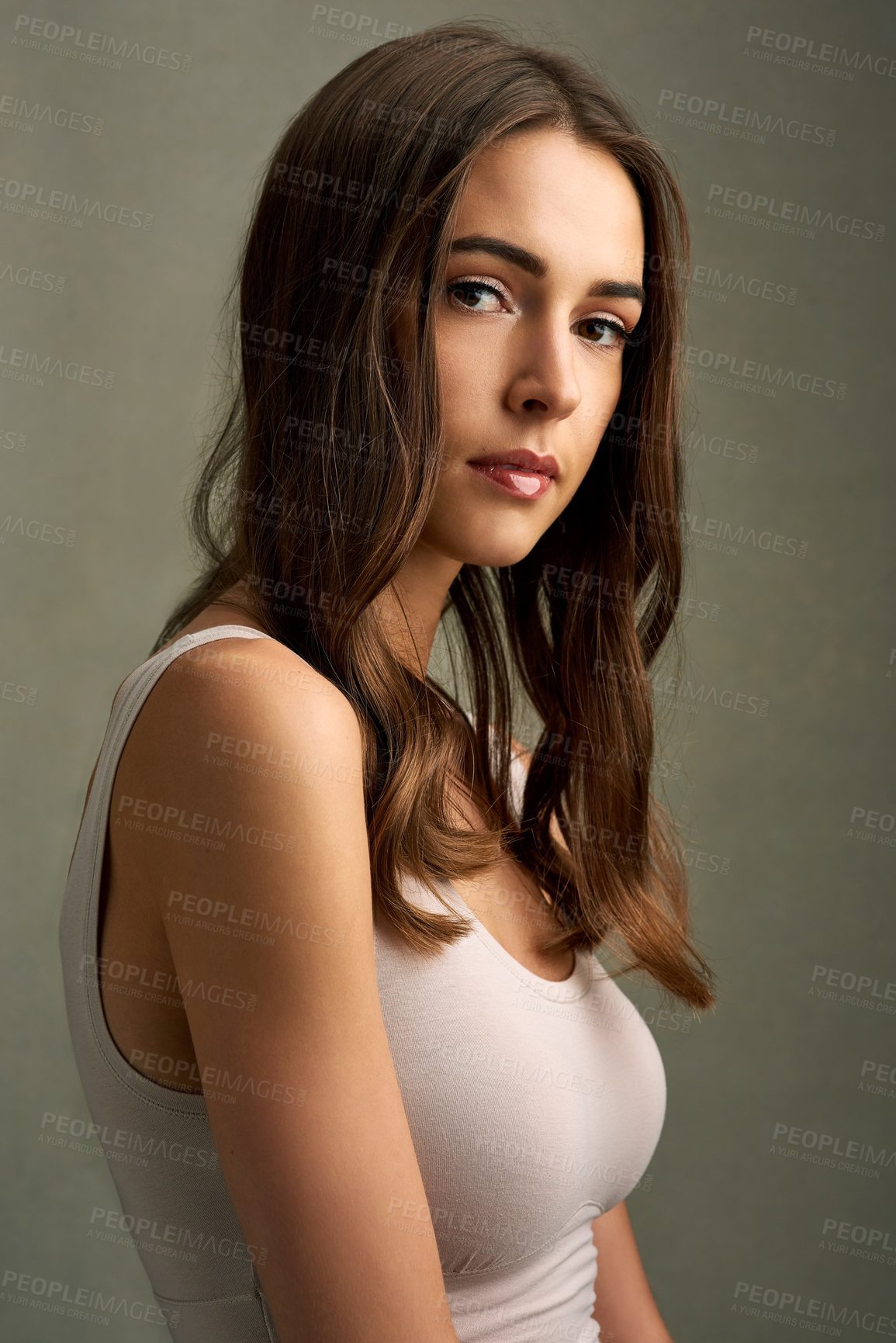 Buy stock photo Studio portrait of an attractive young woman standing against a brown background