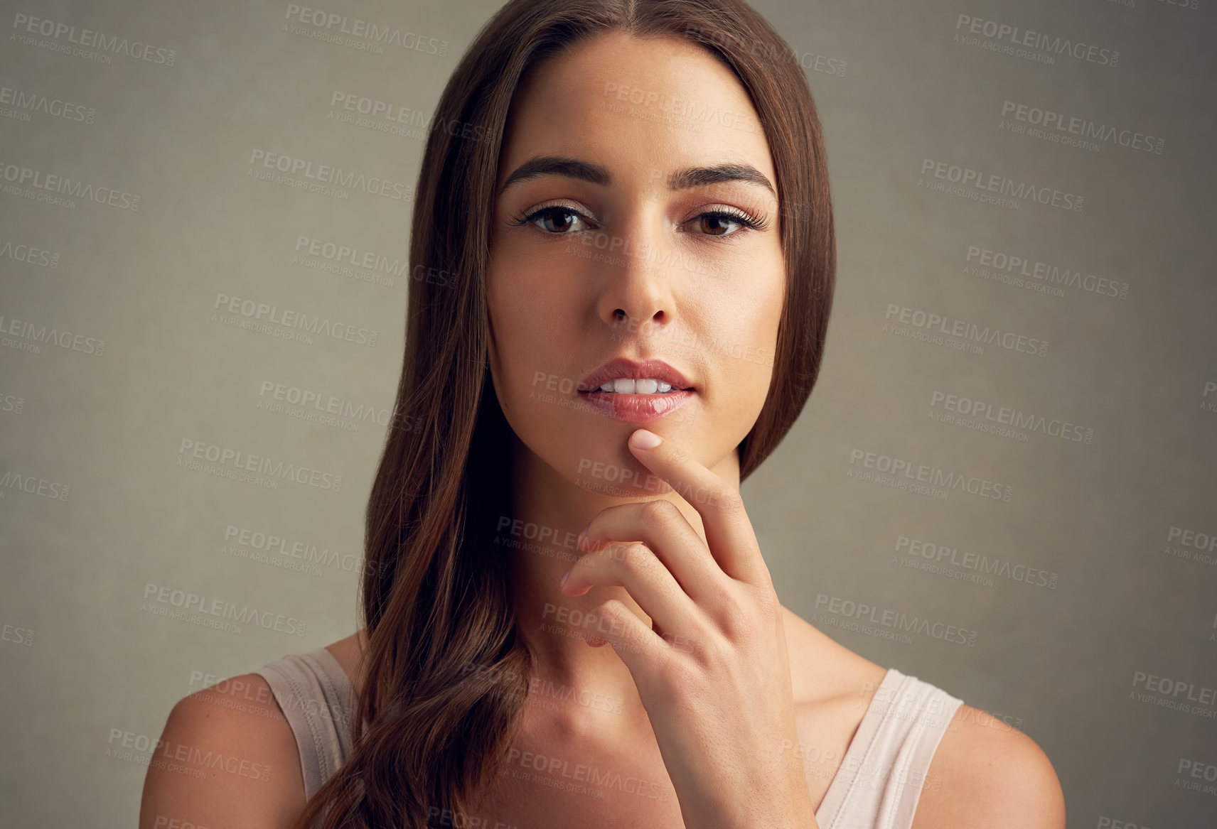 Buy stock photo Studio portrait of an attractive young woman standing against a brown background