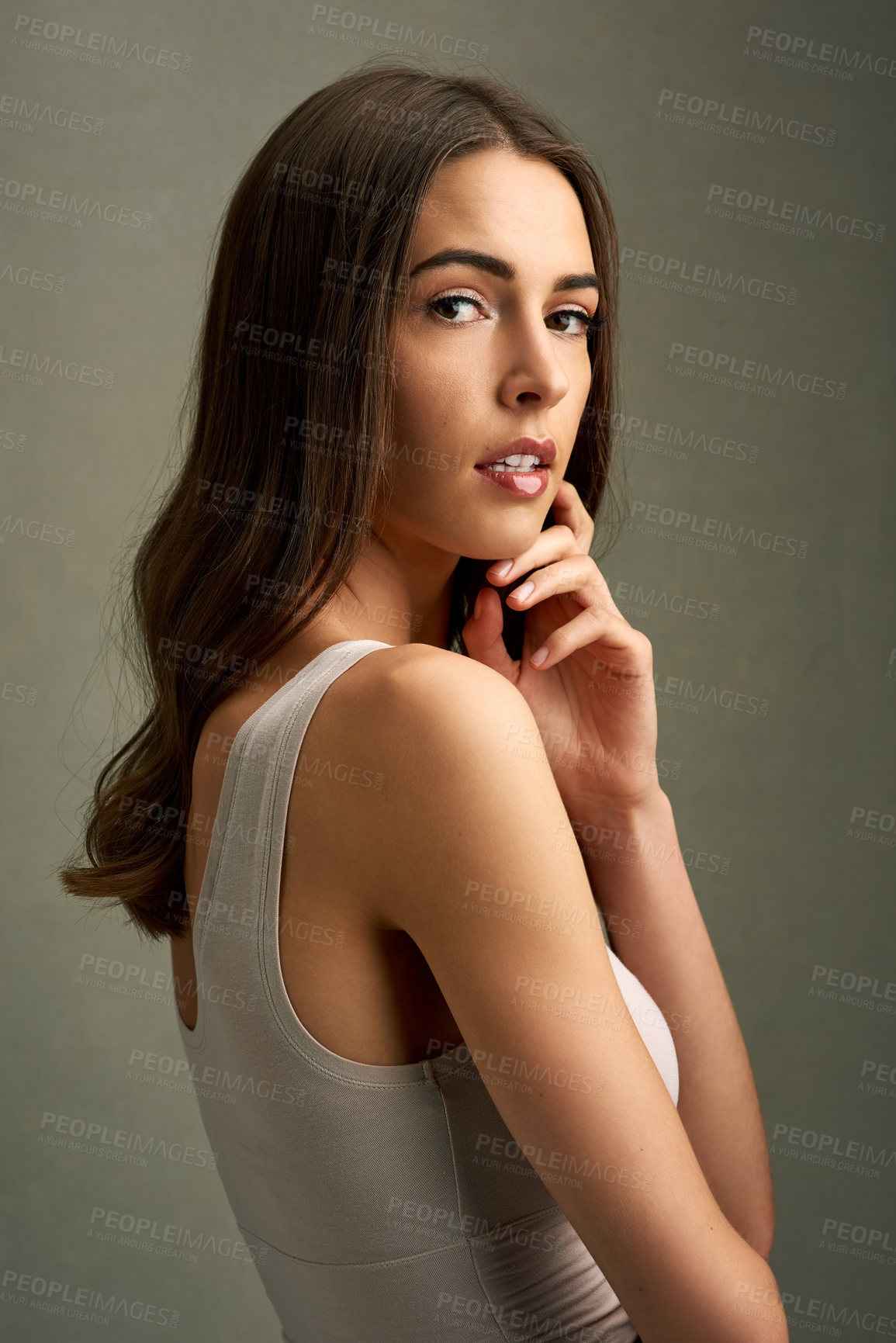 Buy stock photo Studio portrait of an attractive young woman standing against a brown background