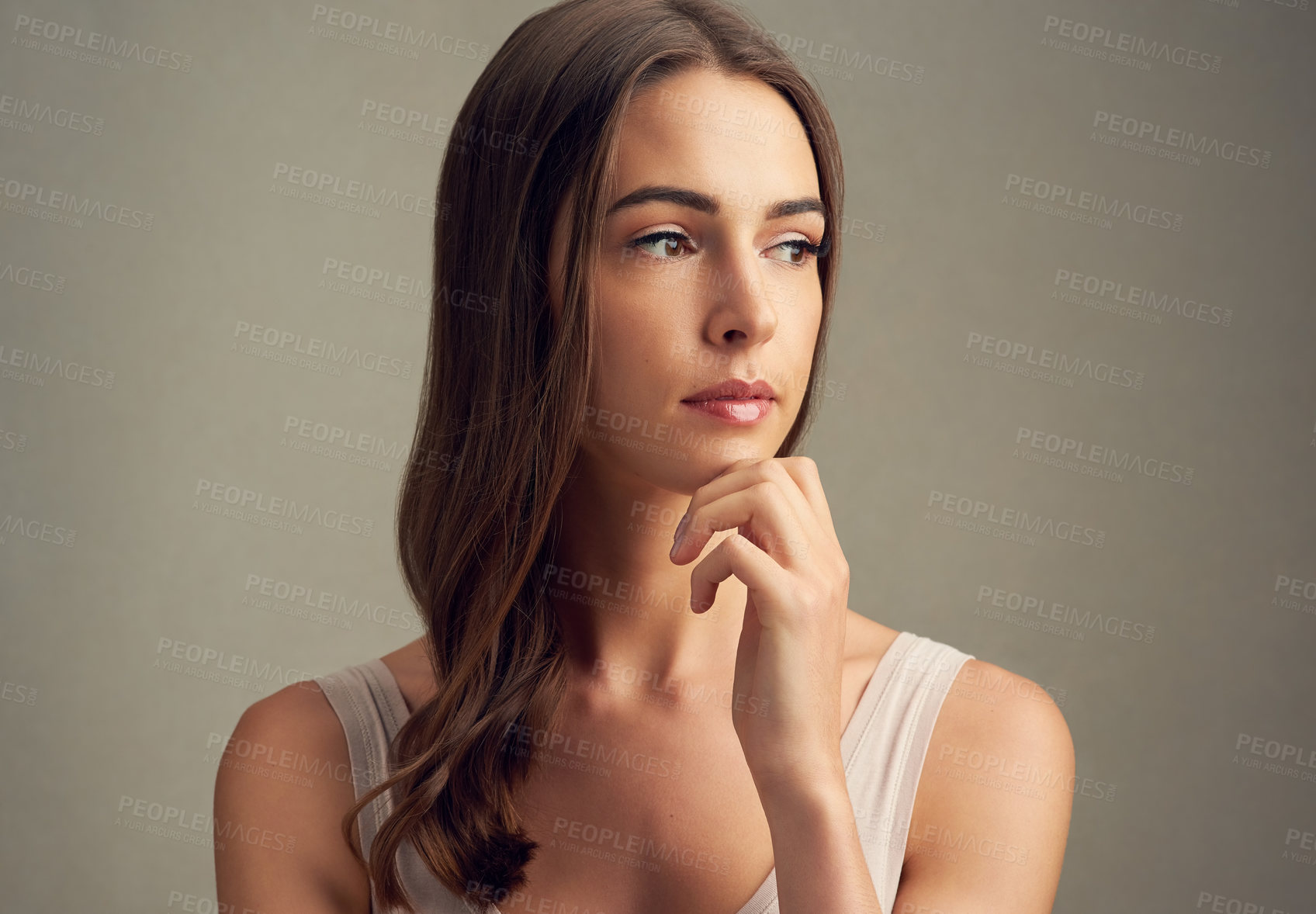 Buy stock photo Studio shot of an attractive young woman standing against a brown background