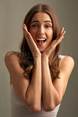 Buy stock photo Studio portrait of an attractive young woman looking excited against a brown background