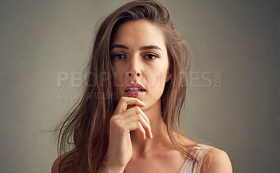Buy stock photo Studio portrait of an attractive young woman standing against a brown background