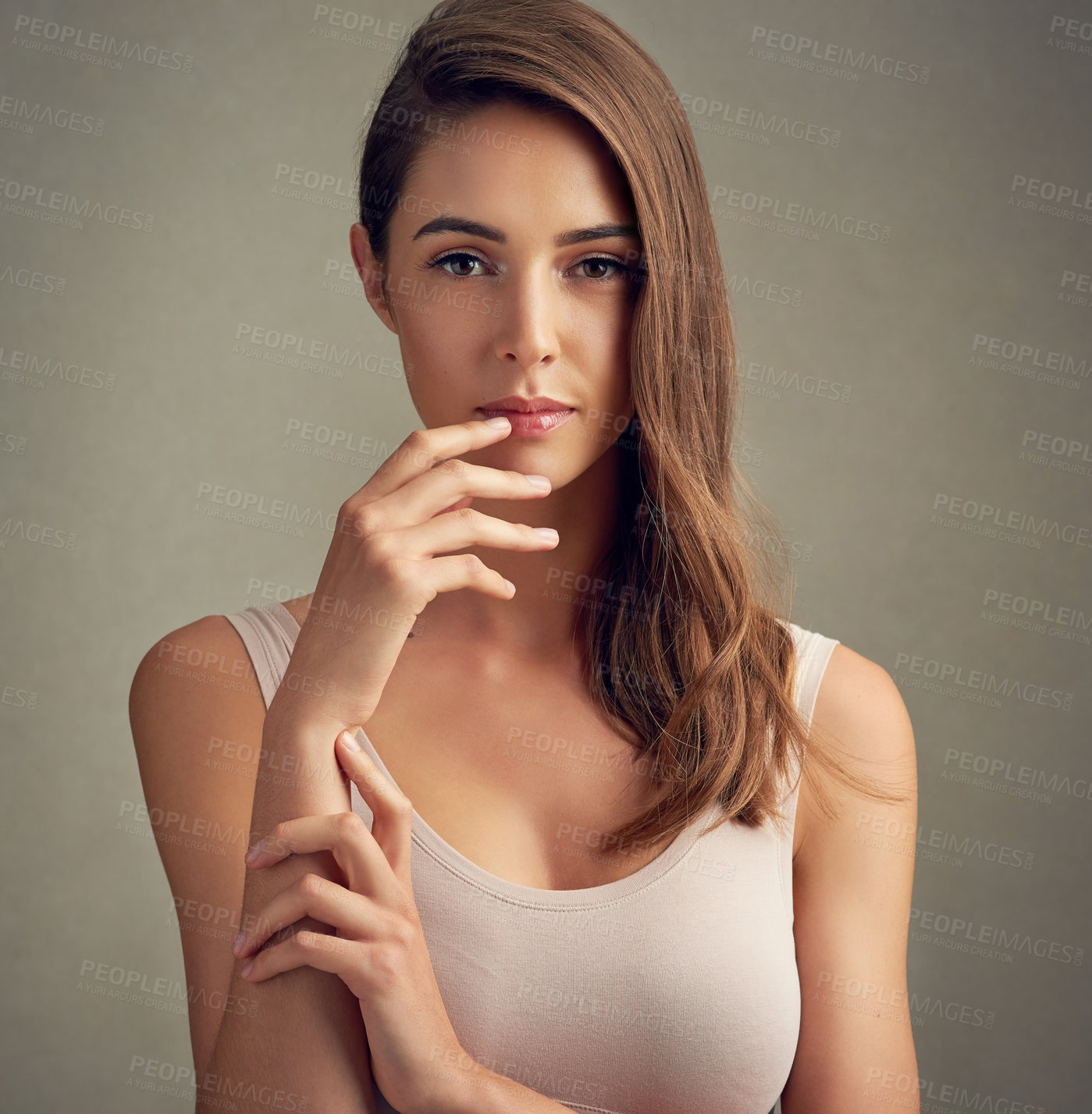 Buy stock photo Studio portrait of an attractive young woman standing against a brown background