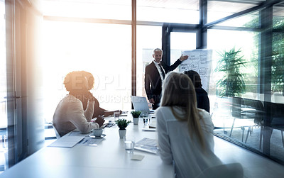 Buy stock photo Shot of a mature businessman giving a presentation to colleagues in a boardroom
