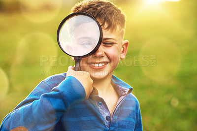 Buy stock photo Portrait of a cute little boy looking through a magnifying glass while standing outside