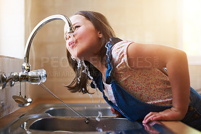 Buy stock photo Shot of a little girl drinking water directly from the kitchen tap at home