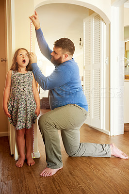 Buy stock photo Father, daughter and measure on wall in home for growth, healthy development and surprised by height increase. People, dad and girl with tape for growing progress, childhood memories and parenting