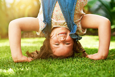 Buy stock photo Portrait of a happy little girl doing a handstand on the grass outside