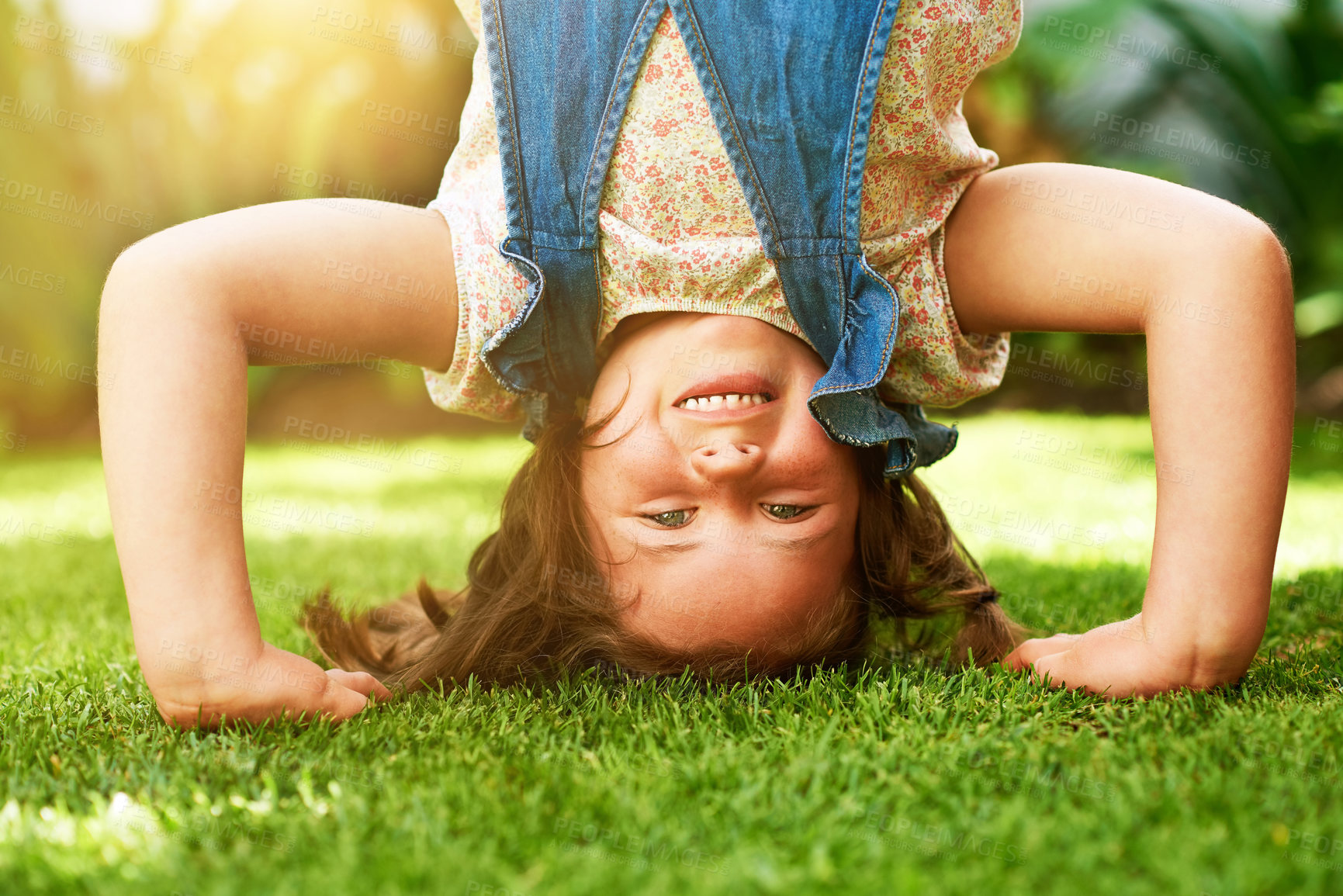 Buy stock photo Portrait of a happy little girl doing a handstand on the grass outside