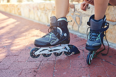 Buy stock photo Closeup shot of a young woman's feet in rollerblades sitting on a park bench