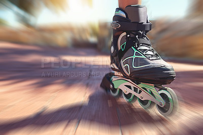 Buy stock photo Closeup shot of a young woman's feet in rollerblades speeding down a park path