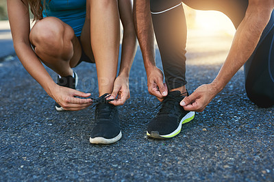 Buy stock photo Cropped shot of a couple tying their shoelaces while out for a run