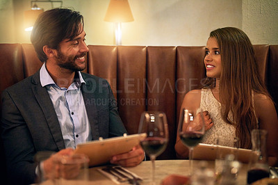 Buy stock photo Couple, restaurant and night date with wine, love and happy communication to celebrate. Young man and woman together for fine dining, valentines day and romantic dinner while reading menu and talking