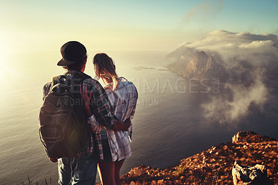 Buy stock photo Rearview shot of an unidentifiable young couple admiring the view from a mountain peak together