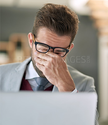 Buy stock photo Shot of a businessman feeling exhausted while using a laptop at his office desk