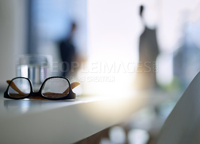 Buy stock photo Shot of glasses on a boardroom desk with two businessmen blurred in the background