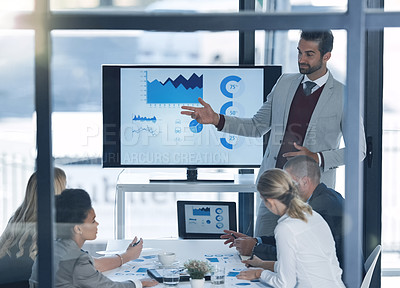 Buy stock photo Shot of a businessman discussing charts on a monitor to businesspeople in the boardroom