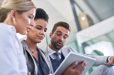 Buy stock photo Cropped shot of a group of businesspeople working together on a digital tablet in an office