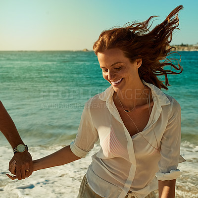 Buy stock photo Shot of a happy young woman running along the beach with her boyfriend