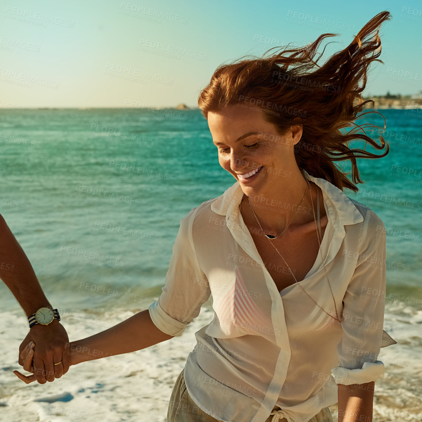 Buy stock photo Shot of a happy young woman running along the beach with her boyfriend