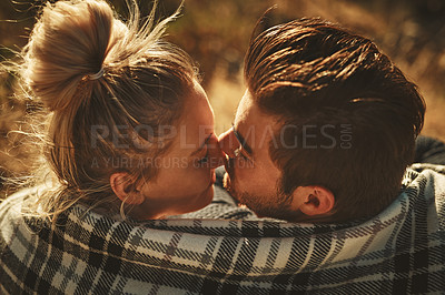 Buy stock photo Shot of an affectionate couple wrapped in a blanket while spending time out in nature