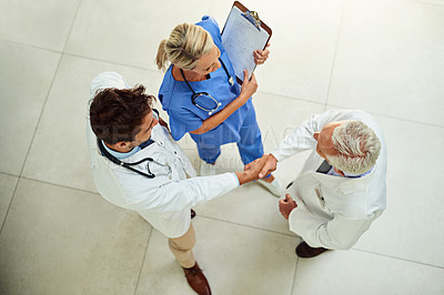 Buy stock photo High angle shot of a team of doctors shaking hands in the hospital