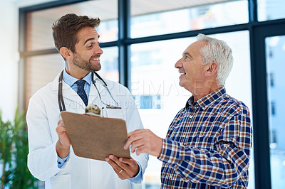 Buy stock photo Shot of a cheerful doctor sharing good test results with his mature patient in the hospital