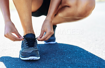 Buy stock photo Cropped shot of a woman tying her shoelaces while out for a run