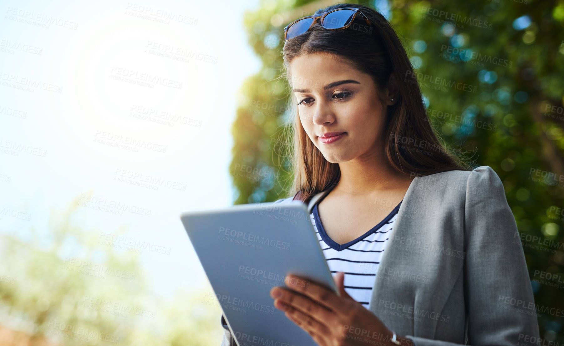 Buy stock photo Cropped shot of an attractive young woman using her tablet while commuting to work