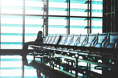 Buy stock photo Shot of an unidentifiable traveler using his smartphone in an empty airport lounge