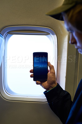 Buy stock photo Shot of a young passenger using his cellphone inside an airplane cabin