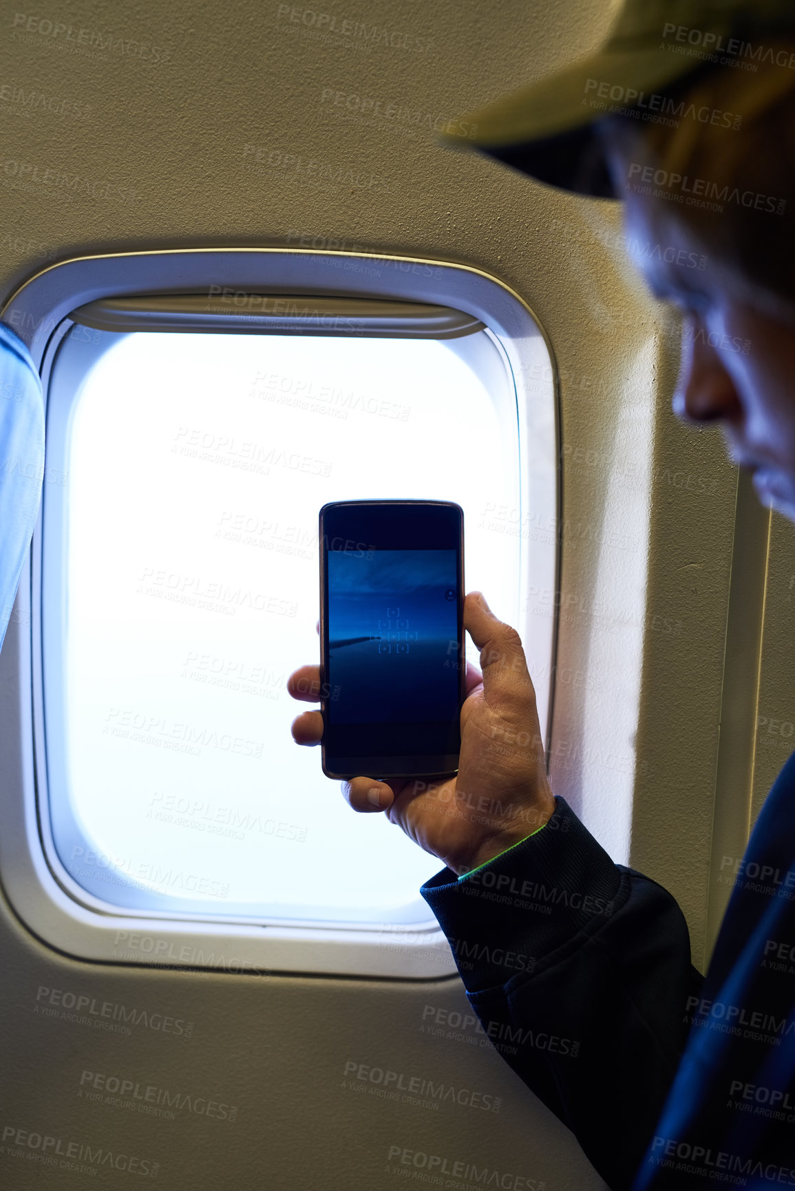 Buy stock photo Shot of a young passenger using his cellphone inside an airplane cabin