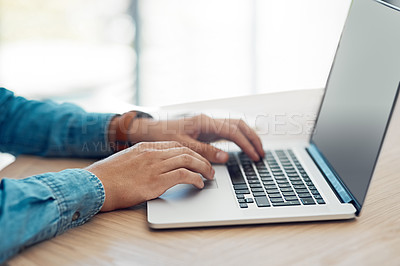 Buy stock photo Shot of an unidentifiable young businessman working on his laptop at a table in the office