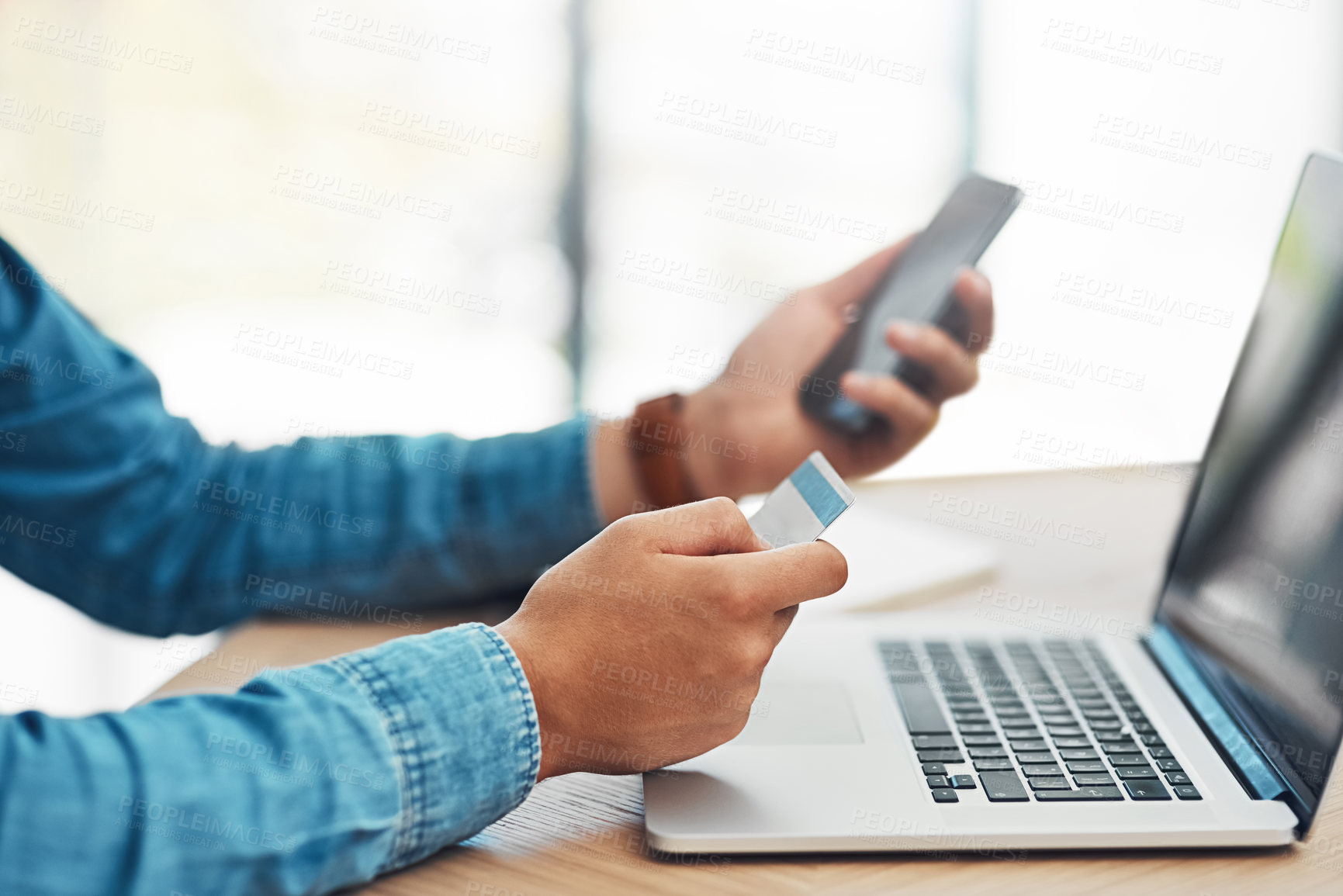 Buy stock photo Shot of an unidentifiable young businessman using wireless technology to make an online purchase in the office