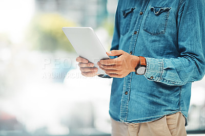 Buy stock photo Shot of an unidentifiable businessman using his tablet while standing in the office