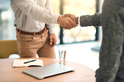 Buy stock photo Shot of two unidentifiable business partners shaking hands over a table in the office