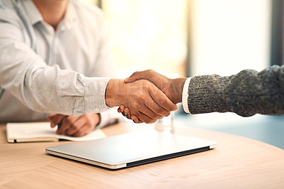 Buy stock photo Shot of two unidentifiable business partners shaking hands over a table in the office