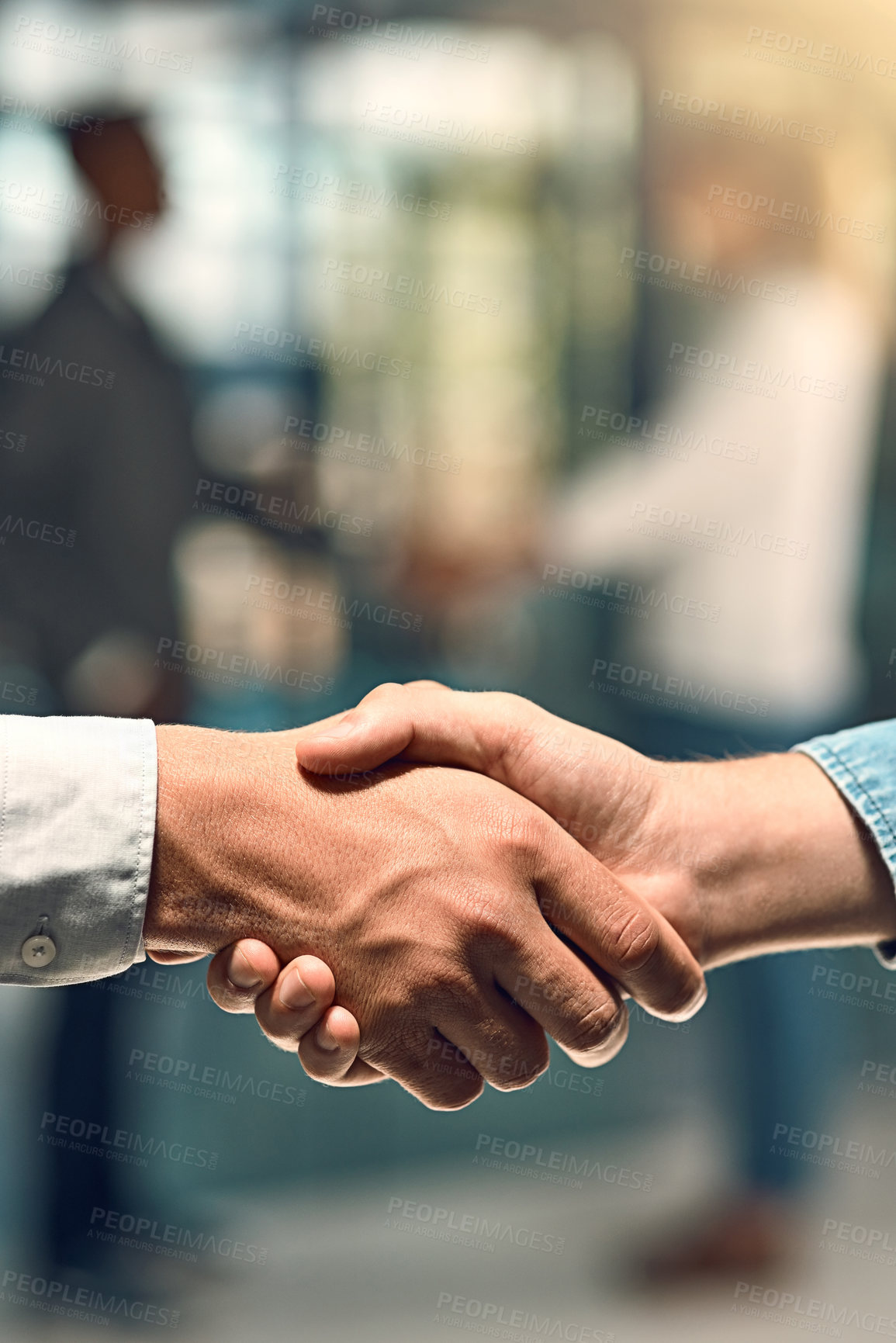 Buy stock photo Shot of two unidentifiable young business partners shaking hands in the office