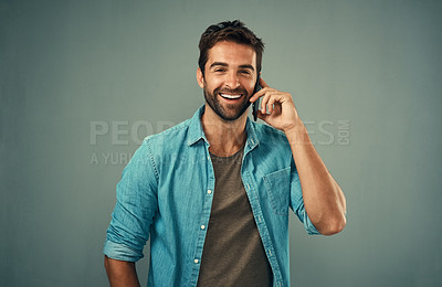 Buy stock photo Studio portrait of a handsome young man talking on a cellphone against a grey background
