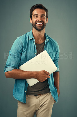 Buy stock photo Studio portrait of a handsome young man holding a laptop against a grey background