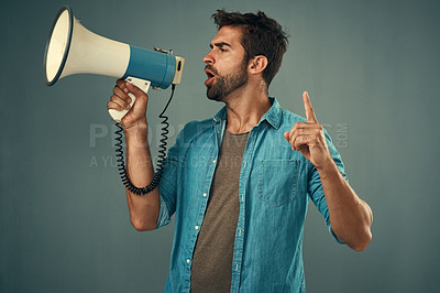 Buy stock photo Studio shot of a handsome young man talking into a megaphone against a grey background