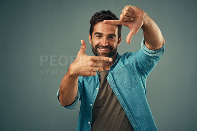 Buy stock photo Frame, hands and face portrait of man in studio on gray background with happiness, confident and smile. Photographer, happy and male person with hand sign for picture, photography and finger border