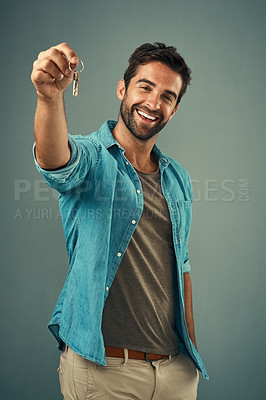 Buy stock photo Studio portrait of a handsome young man holding a set of keys against a grey background