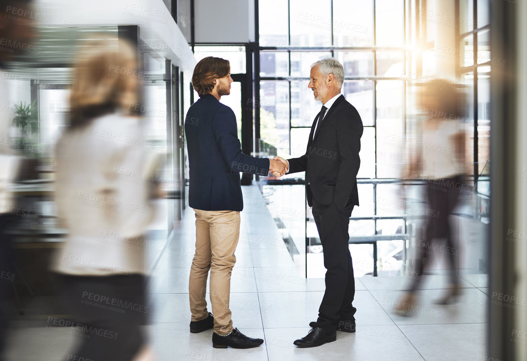 Buy stock photo Shot of two businessmen shaking hands in a busy office